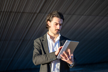 Confident And Successful Businessman Holding Tablet Near Office Building, Authentic Online Communication And Email Review For Client Agenda Management.