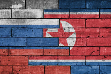 colourful painted big flag of russia and flag of north korea on a massive old brick wall background. concept