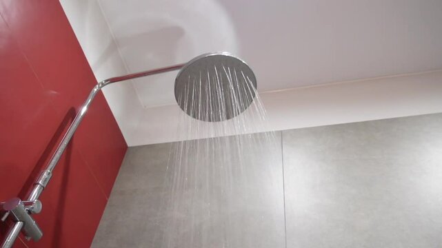 Water running from rain shower head in dark red modern luxury bathroom. SLO MO LD water flow from the rain shower head. Water flows from the shower head. 