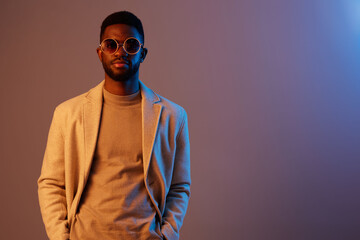 Stylish man wearing sunglasses and a neutral outfit, exuding confidence against a colorful gradient background Modern fashion concept with urban vibes