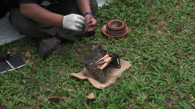 Close up of the activity of an Asian male adventurer cooking grilled shrimp using charcoal and wood. The bushcraft concept makes grilled shrimp with simple equipment in the lush wilderness