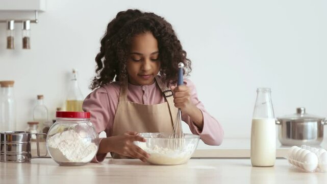 In a cozy home kitchen, a young girl joyfully mixes ingredients in a bowl, cooking pastry by herself