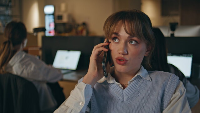 Late businesswoman talking smartphone calling at corporate workplace closeup