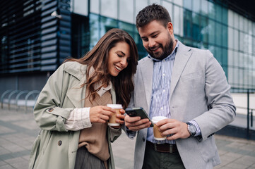 Business people using smartphone and drinking coffee outdoors