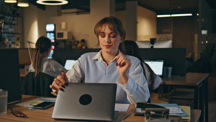 Late worker closing laptop ending work at open space office workplace closeup