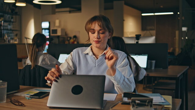 Late worker closing laptop ending work at open space office workplace closeup