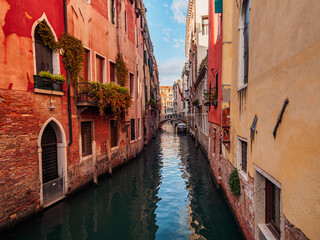 View of a canal in Venice in the Castello Quarter during the day, with multicolor residential buildings decorated with flowers and an arch bridge, UNESCO World Heritage Site, Venice, Veneto, Italy.