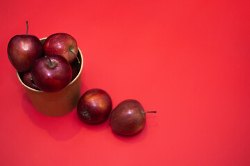 red apples in a large paper cup on a red background