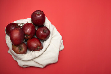 red apples in an eco bag on a red background