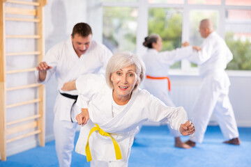 Irate mature female karate practitioner fighting with her opponent in sports hall