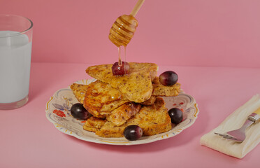 Slices of French toast with grapes and honey being drizzled over them.