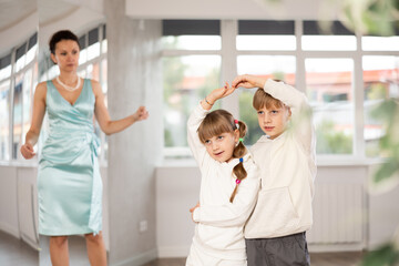 Motivated preteen ballroom dancers, girl and boy in sportswear practicing elegant dance moves in...