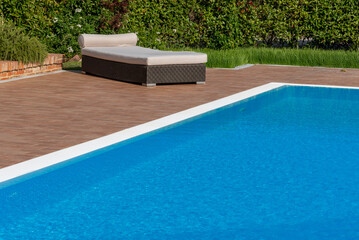 Swimming pool with pool lounger with soft mattress on background of green hedge
