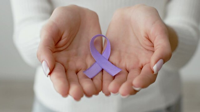 Hands hold a purple ribbon, a symbol of domestic violence awareness, emphasizing the importance of support and prevention in communities. The setting is calm and inviting, promoting dialogue.