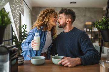 happy couple prepare oatmeal with milk for breakfast together at home