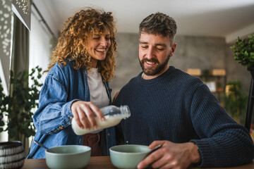 happy couple prepare oatmeal with milk for breakfast together at home