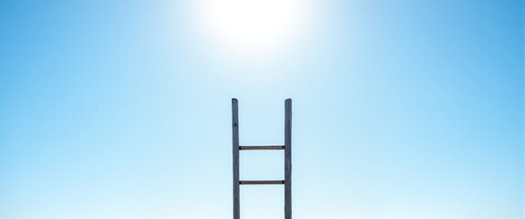 Ladder reaching towards a bright sun against a clear sky symbolizing hope and personal fulfillment in an open space
