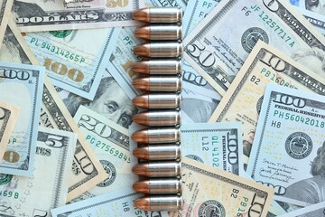 Pistol bullets and cartridges lies on many dollar bills