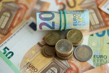 Roll of euro currency money bills and many euro cents on banknotes of european union