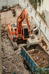 Excavator removing debris from a demolition site and dumping it into the truck