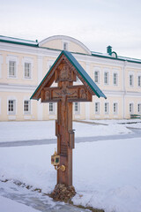 Wooden cross is standing in the snow next to a building