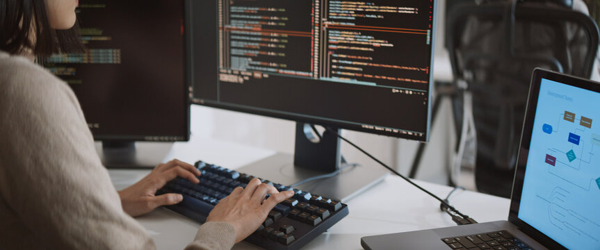 Young adult Asian female software developer coding program on desktop computer. Woman work from home, remote working, freelance programmer job, smart digital nomad lifestyle concept. Close Up