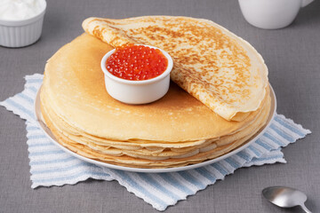 Delicious stack of golden pancakes served with cream and caviar on a rustic table