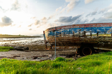Old boat left on a small beach along the Ring of Kerry route. Rugged coast of on Iveragh Peninsula...