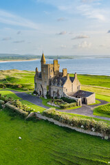 Classiebawn Castle on a backdrop of picturesque landscape of Mullaghmore Head. Spectacular sunset view with waves rolling ashore. Signature point of Wild Atlantic Way, Co. Sligo, Ireland