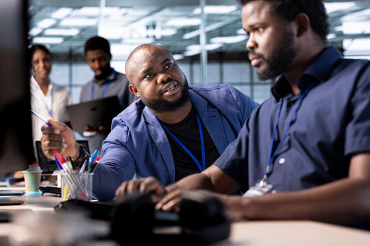 Unhappy manager admonishing technician after failing to properly reconfigure server farm to optimize it for data processing requirements of customers, berating him while pointing to coding mistakes