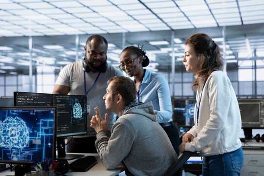 Manager doing team meeting with technicians, delegating tasks in high tech data center office. Supervisor doing brainstorming with IT specialists, telling them how to monitor AI supercomputers