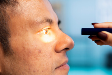 Optometrist performing a vision test in a modern clinical office. Indian patient undergoing an eye exam, optician using diagnostic tools for eyesight correction at consultation. Close up.