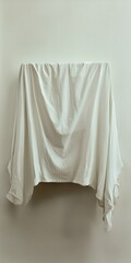 Fototapeta premium A draped white fabric hanging against a plain wall, creating a soft, minimalist aesthetic.