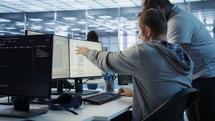 Programmer requesting help from manager while working on computer in data center, monitoring...