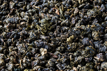 Pile of green dry leaves of tea oolong with milk aroma, closeup. Background of dried green tea...