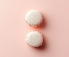 Obraz premium Two white macarons on soft pink background with minimalist aesthetic