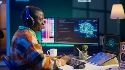 African american worker at desk using personal computer for programming and data analysis. Male networking expert working at home, manages information technology and data center on pc. Camera A.