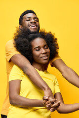 Obraz premium Happy couple with natural hair expressing love in matching yellow shirts, set against a bright yellow background, ideal for relationship and positivity themes