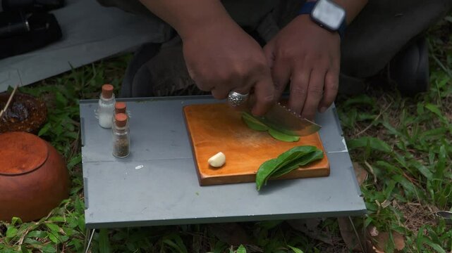 Close up of the activity of an Asian male adventurer cooking lime leaf rice using charcoal and wood. The bushcraft concept makes lime leaf rice with simple equipment in the lush wilderness