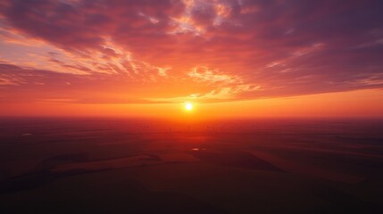 Fototapeta premium An aerial shot of a wind farm at sunset, with turbines silhouetted against the vibrant orange and purple hues of the sky, creating a stunning contrast of nature and technology.