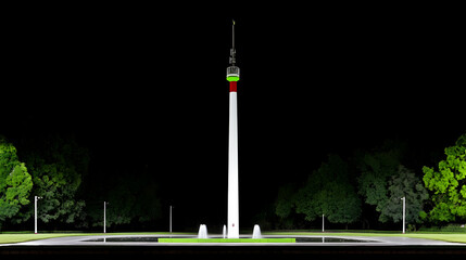 Obraz premium Illuminated tower at night, surrounded by trees and a plaza.