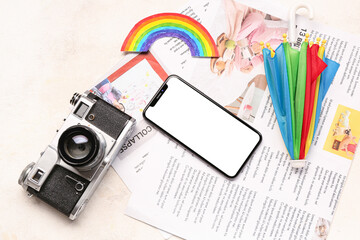 Mobile phone with photo camera, rainbow, umbrella and newspapers on grunge background. Weather forecast concept