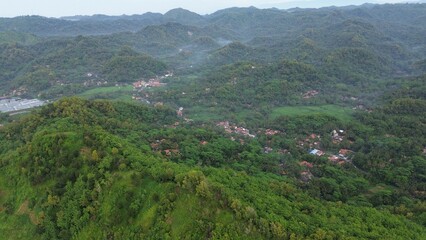 Drone view of hills with trees and agricultural fields with footpaths on the Silayur hills, Kebumen