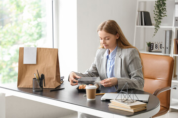 Happy young woman with sushi and paper bag in office