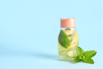 Sports bottle of lemonade with cucumber and mint on blue background