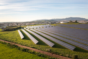 Drone shot of solar panels arranged on vast agricultural land during sunny day. The field is...