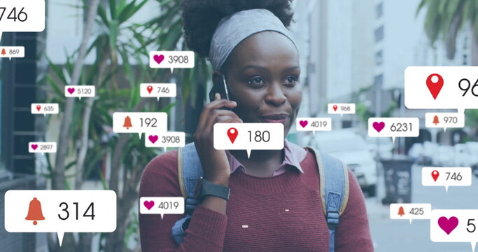 Image of social media notifications over happy african american woman talking on smartphone