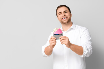 Young man holding wallet with credit cards and money on white background