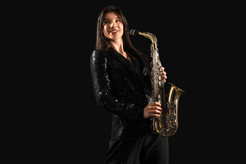 Beautiful young woman with saxophone on dark background
