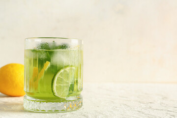 Glass of tasty lemonade with mint and lime slices on white background